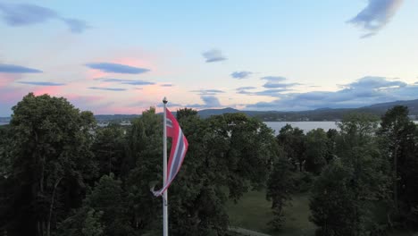 Flag-of-Norway-in-the-wind-on-the-shore-of-the-fjord