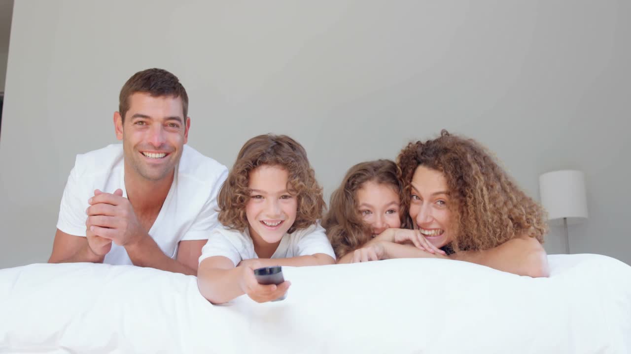 Smilende familie ser tv