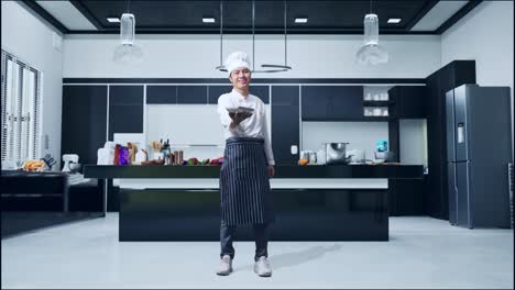 full body of asian man chef smiling and giving a dish to camera while standing in home kitchen