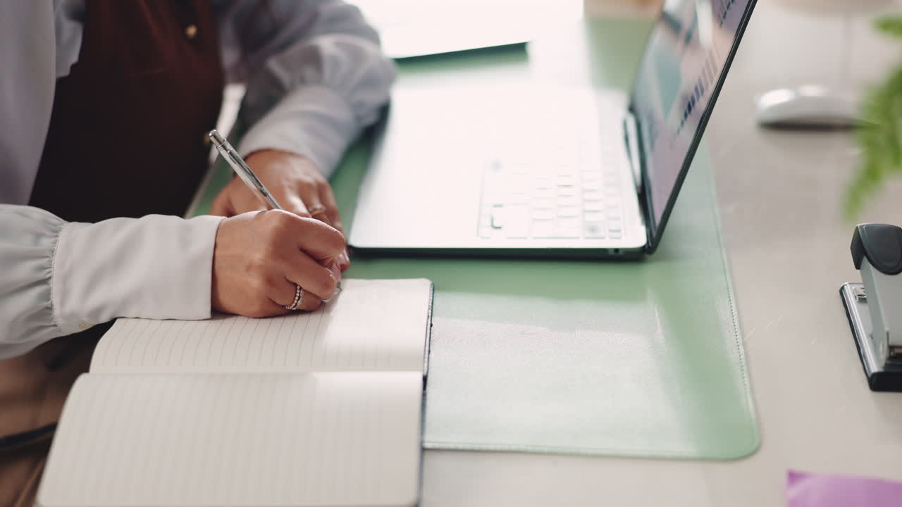 Working on a laptop and taking notes in a notebook