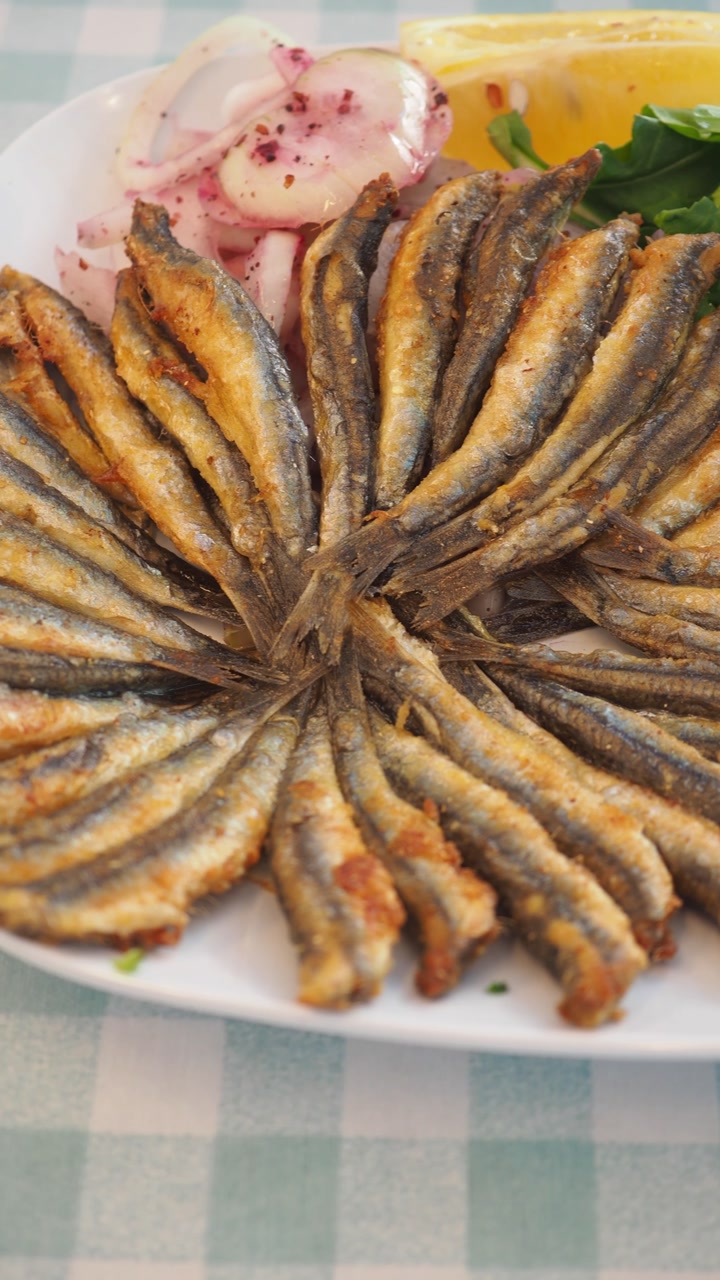 Delicious Fried Anchovies Served with Fresh Salad, Lemon, and Onions