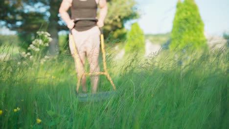 cropped view of a man with push manual lawn mower cutting tall grass