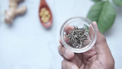 mano sosteniendo un pequeño tazón de vidrio con hojas de té blanco