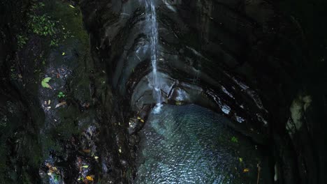 small cascade trickle waterfall falls into magical blue pool, aerial tilt up reveal