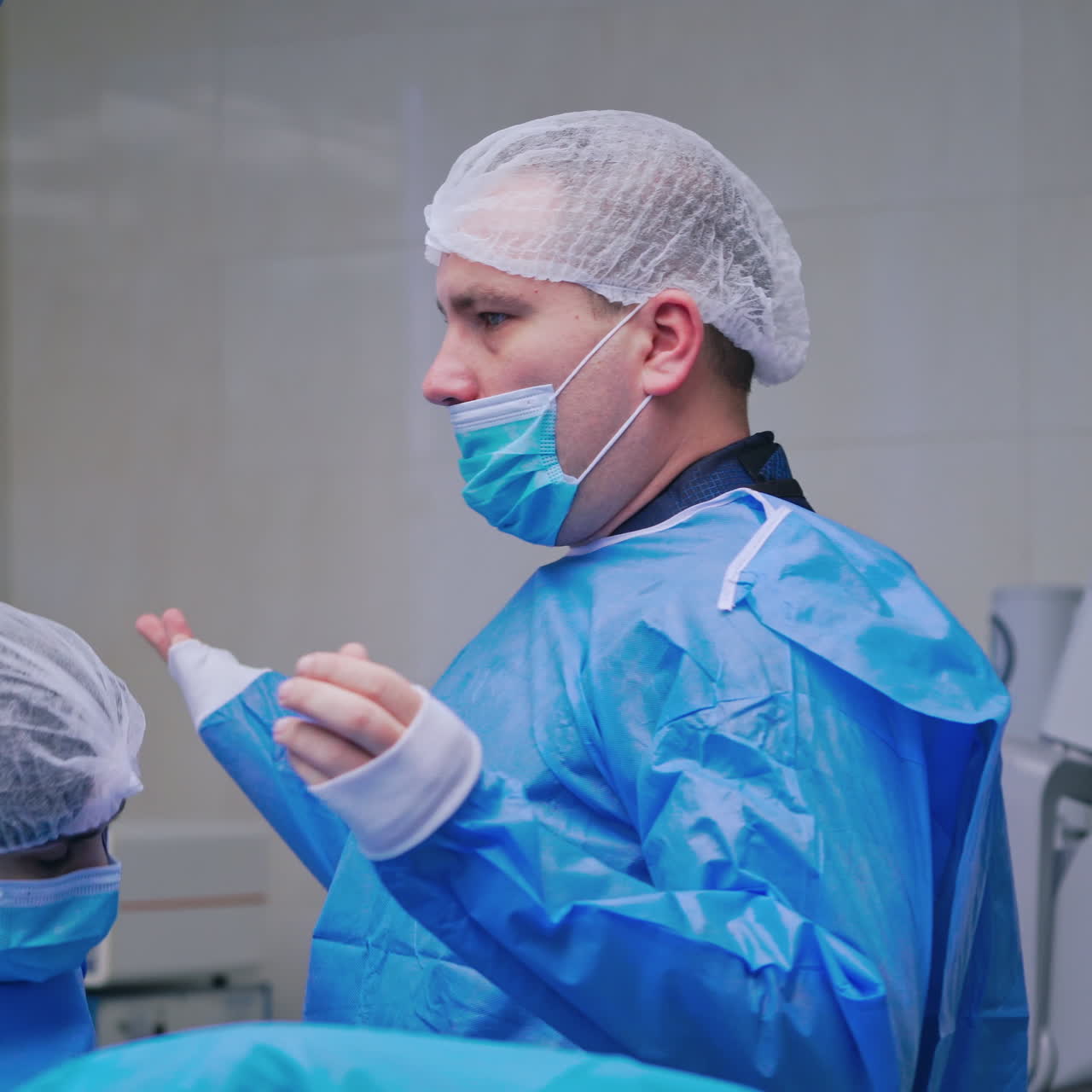 Medical nurse helps doctor to dress sterile clothing. Assistant dresses a surgical gown to a male surgeon in the operating room.