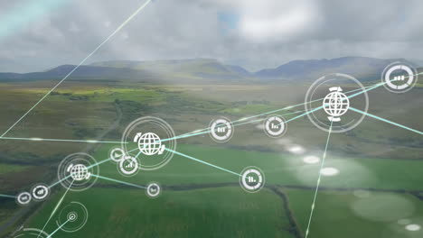 animación de iconos conectados sobre vista aérea de vehículo en movimiento junto a tierra verde contra montañas