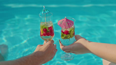 una pareja disfrutando de cócteles junto a la piscina.