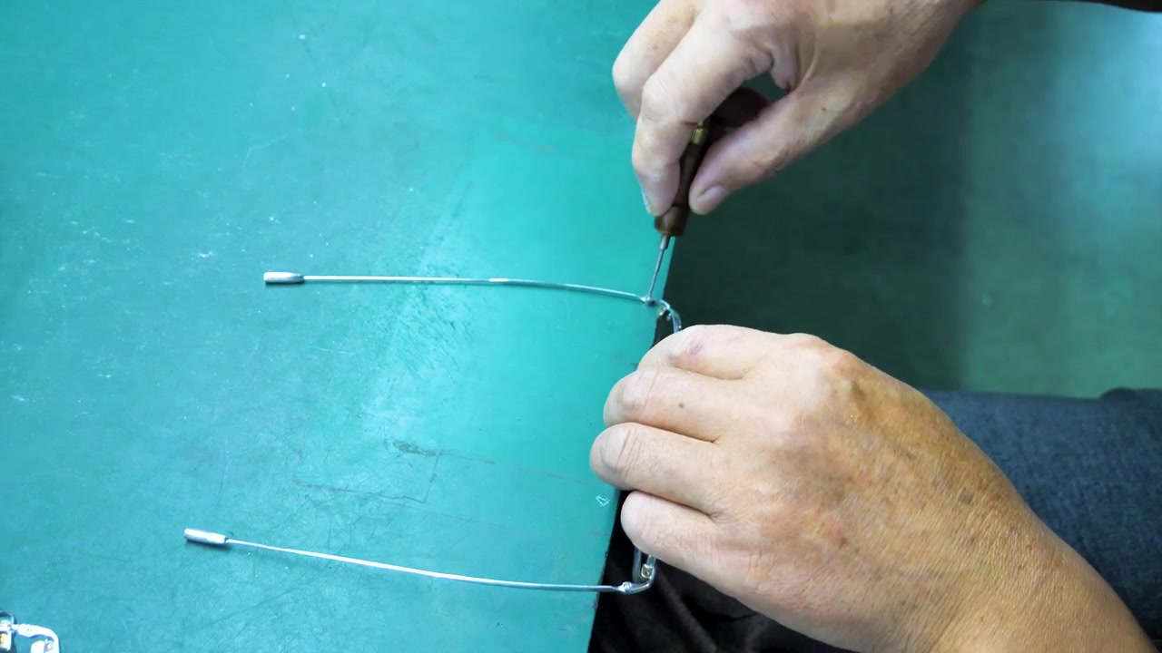 Workers in a spectacle factory tightening screws on glasses frames. Jiangsu Province, China.