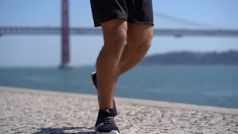 low section of man running on pavement at riverside