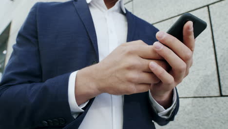 Businessman-texting-message-on-smartphone-at-street.-Executive-using-cellphone