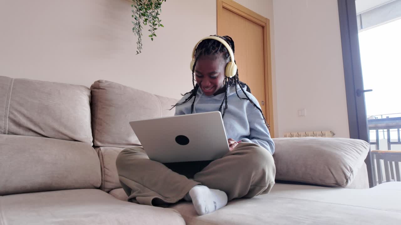Woman using laptop on couch with headphones
