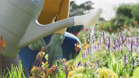 Portrait-of-smiling-african-american-mother-and-daughter-gardening-together-in-sunny-garden