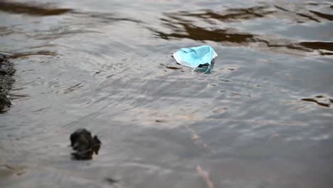 Used-surgical-mask-floating-down-on-the-river-on-an-overcast-day