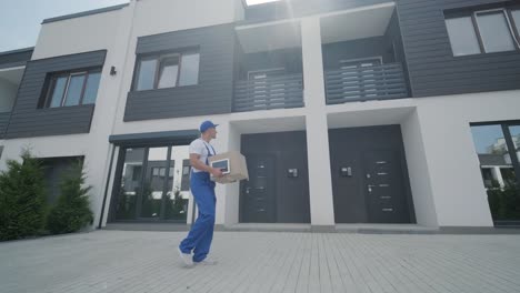 young courier holding a parcel and tablet walking on the street to deliver a box directly to a customer home.