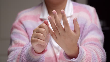 close-up of an individual pinching her fingers one by one, massaging herself to relive the pain and inflammation she is feeling