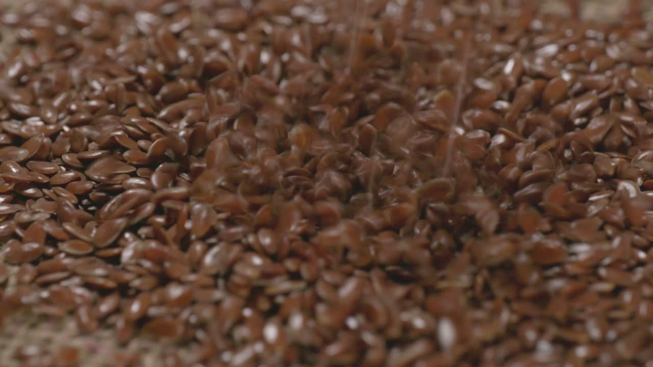 flax seeds falling in the jutt gunny textured cloth, 4k, stable shot