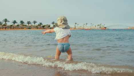 Niedliches-Kind,-Das-Am-Strand-Des-Resorts-Im-Wasser-Spaziert.-Baby-Junge-Spielt-An-Der-Küste.