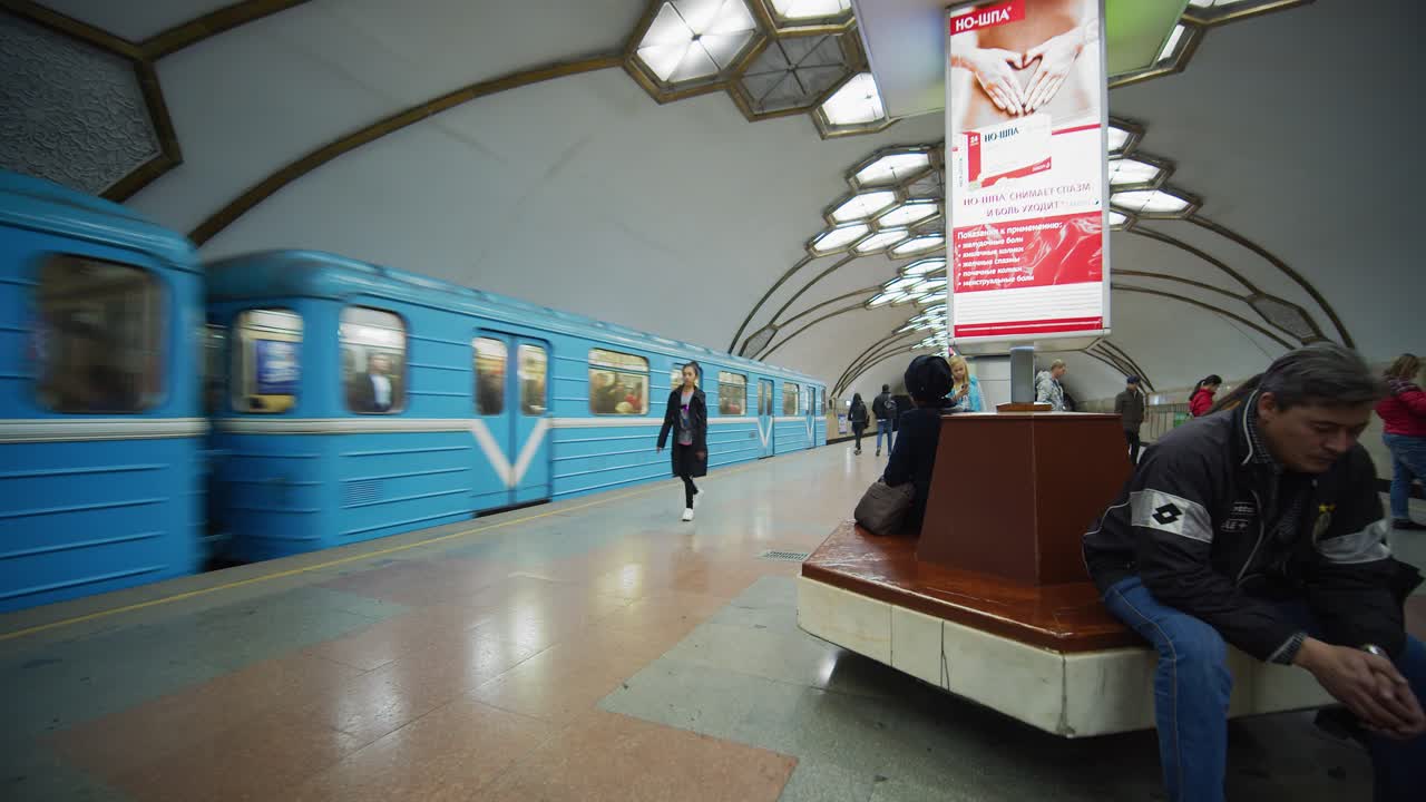 A blue metro train at a busy station platform