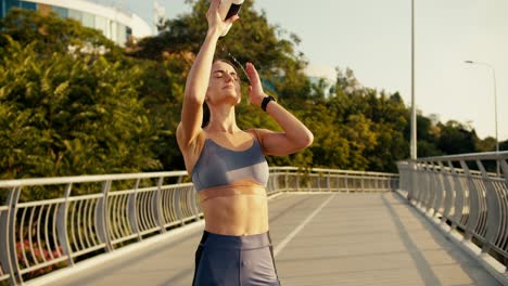 Una-Deportista-Feliz-Con-Uniforme-Deportivo-De-Verano-Bebe-Agua-Y-Una-Botella-Especial-Y-Luego-Se-La-Vierte-En-La-Cara.-Una-Chica-Cansada-Después-De-Correr-Se-Lava-La-Cara.