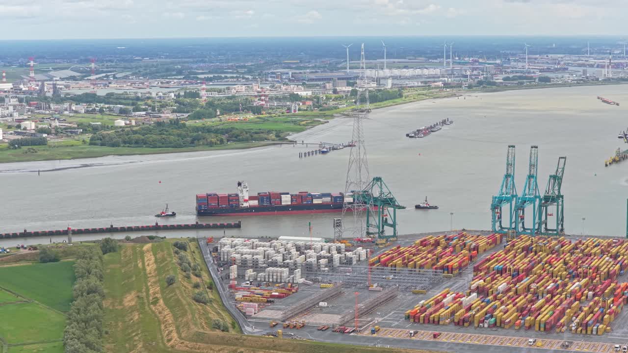 Shipping dock with container stacks, cranes, and vessels, aerial capture