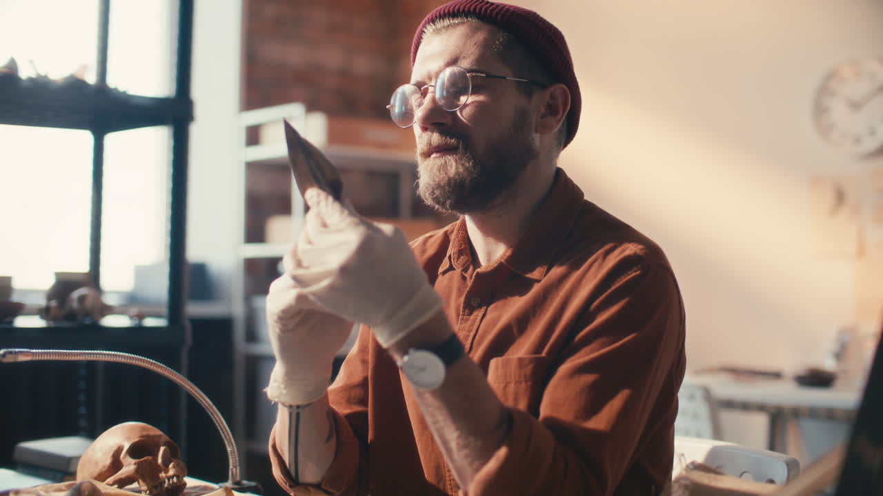 arqueólogo con guantes examinando la punta de la lanza en el laboratorio