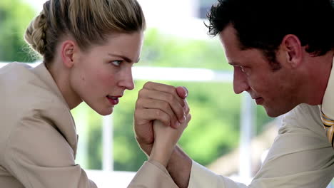 businesswoman and businessman arm wrestling