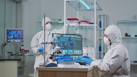 químico en traje de ppe escribiendo en la computadora comprobando el desarrollo de virus