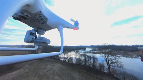 close-up side view of dji phantom 4 quadcopter drone flying forward towards the winding river