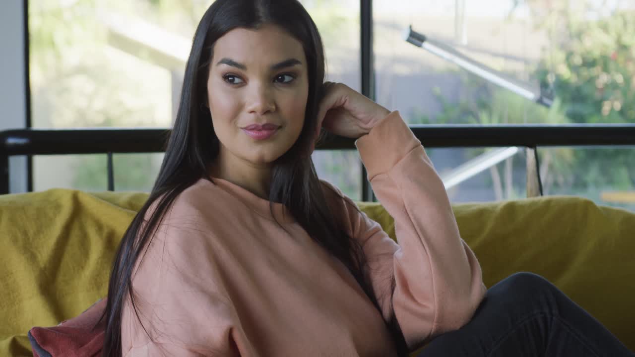 video de una mujer biracial sentada en el sofá