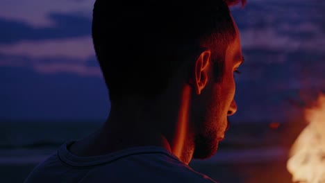 Man watching a bonfire at sunset