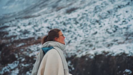 a spiritual blonde lady in awe of beauty of nature and icy waterfalls of dynjandi - westfjords, iceland - revealing shot meditating