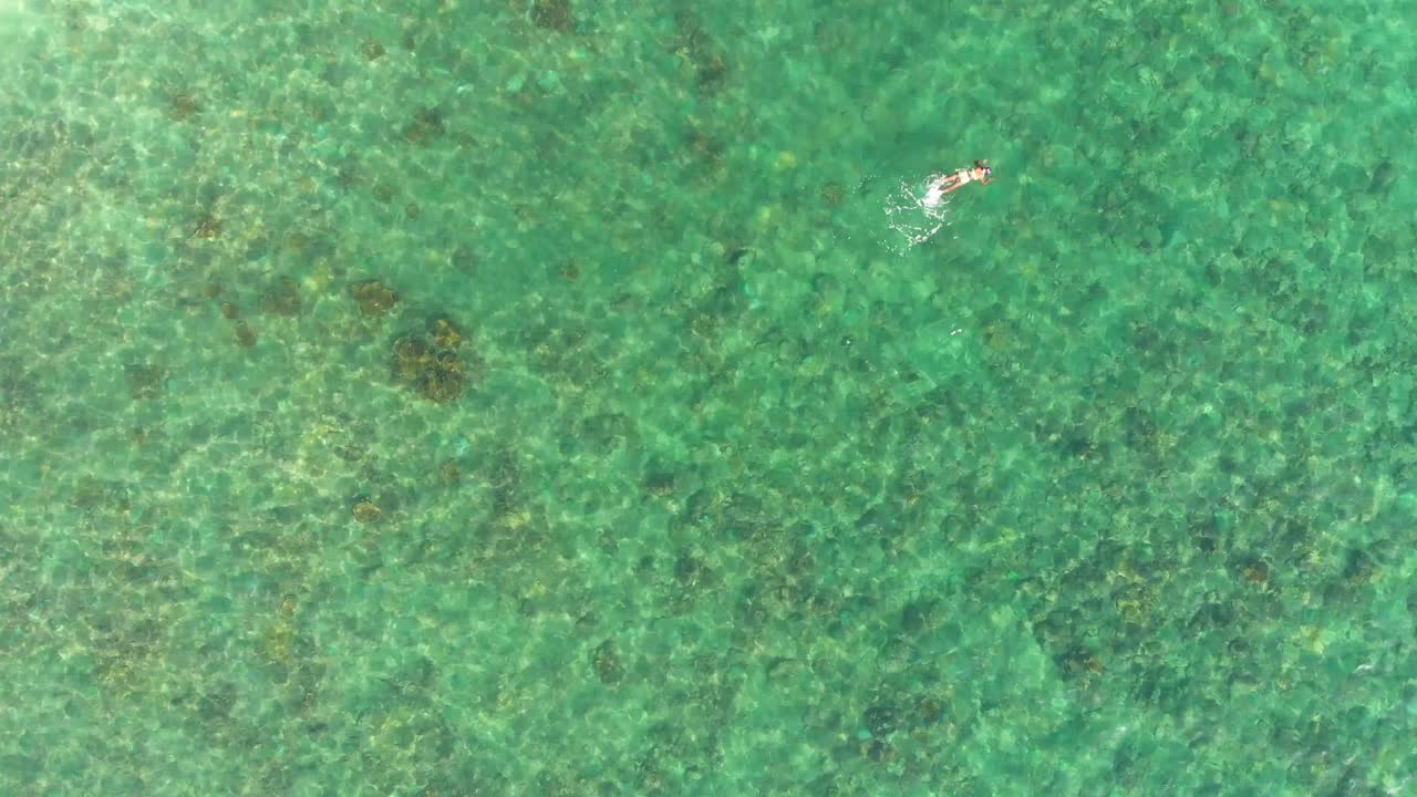 This is drone footage of a girl swimming in Arnos Vale Beach located on the Caribbean island of Tobago.
