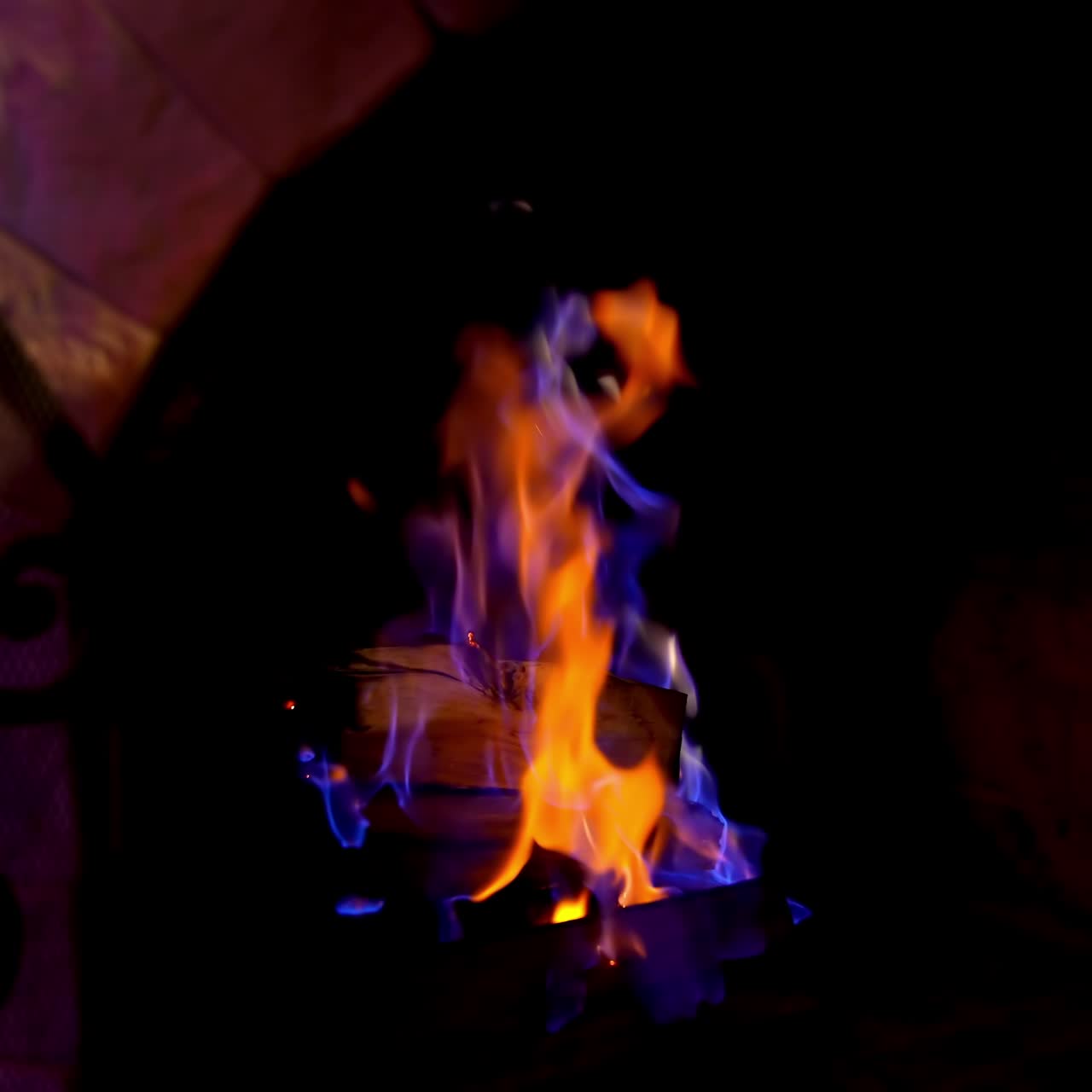 Blue and orange flame in modern fireplace. Wooden logs burning in brick fireplace. Cozy atmosphere at home in winter. Close-up