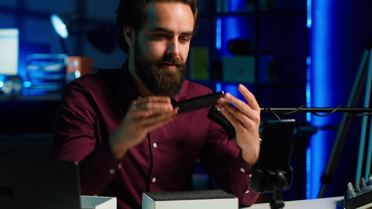 la estrella de los medios en un estudio iluminado con neón presenta un teléfono móvil del video de patrocinio de la marca