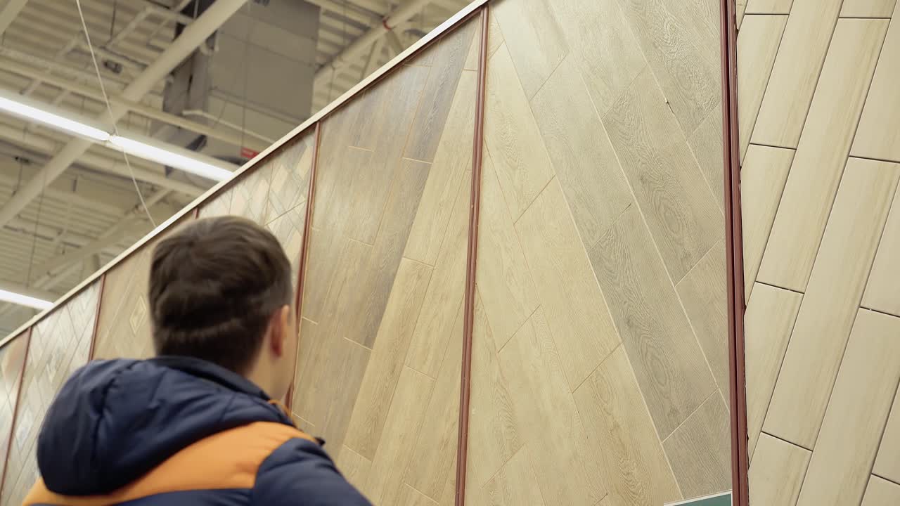 un joven elige un piso que cubre un laminado en una tienda de materiales de construcción