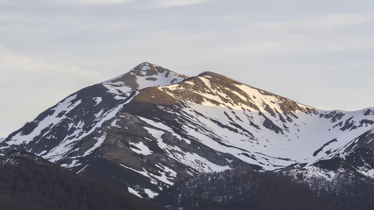 Crinale montuoso con alberi sotto un cielo nuvoloso