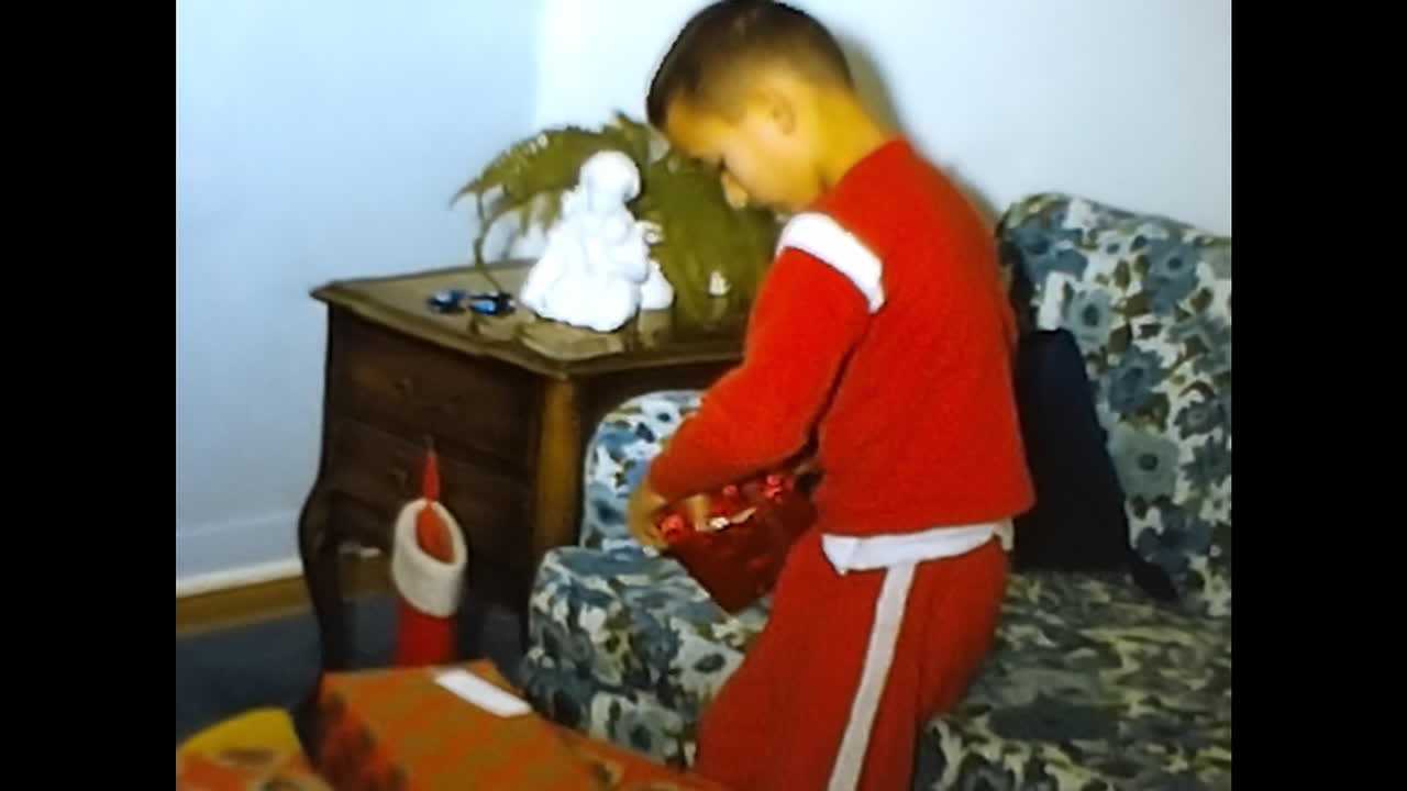 Young Boy Engages in Playtime With Toys in a 1970s American Room. CIRCA USA - 1970s: A young boy is actively playing with various toys in a room captured on a 1970s video archive from the USA.