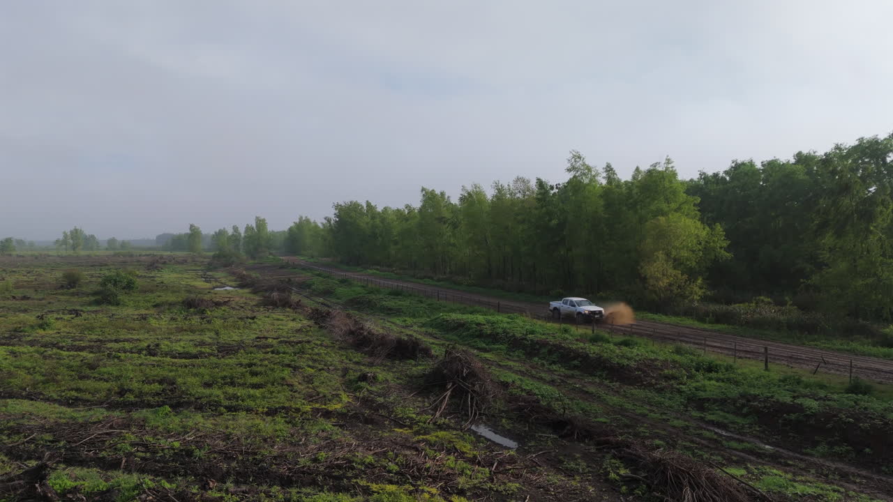 Aerial view of pickup truck traveling along dirt road through woods, Argentina