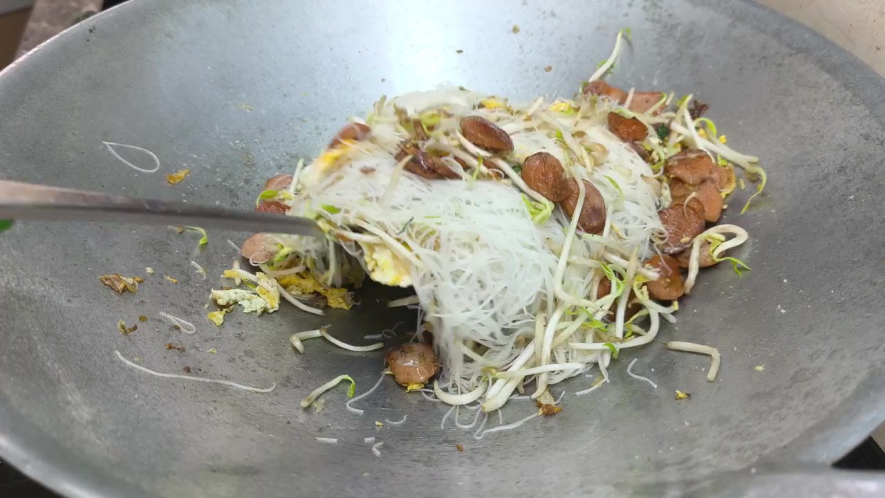 Délicieux vermicelles de riz sautés cuits avec des œufs brouillés et des saucisses tranchées. Assaisonnés de poivre noir pour un arôme savoureux. Un plat de nouilles asiatique appétissant.