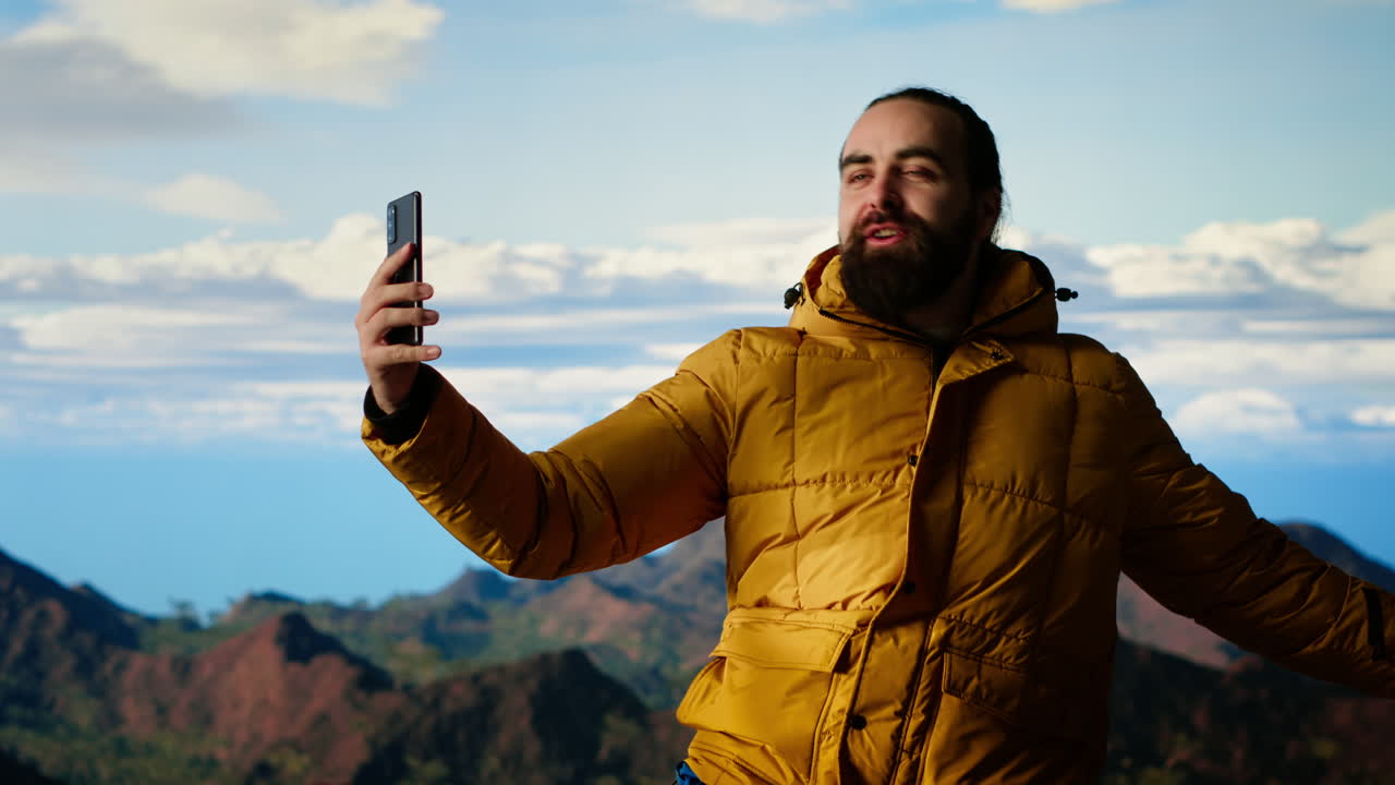creador de contenido masculino grabando un video rodeado de picos de montaña