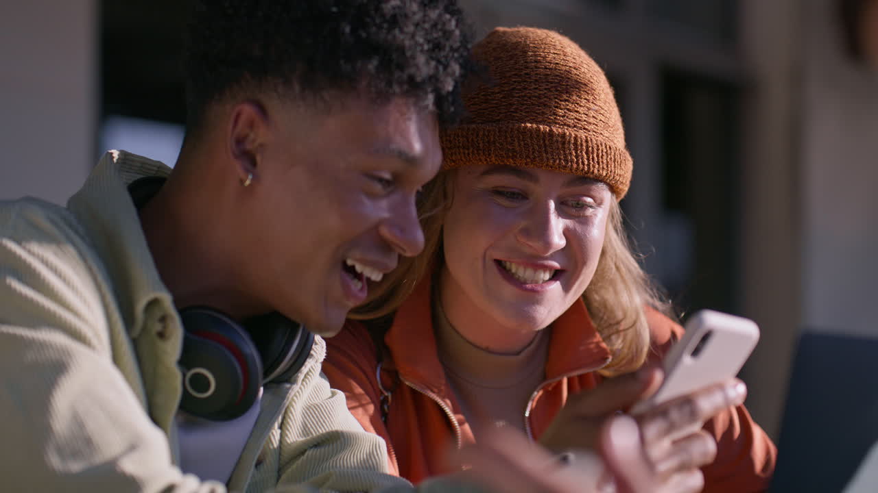 Two young adults looking at a phone and smiling