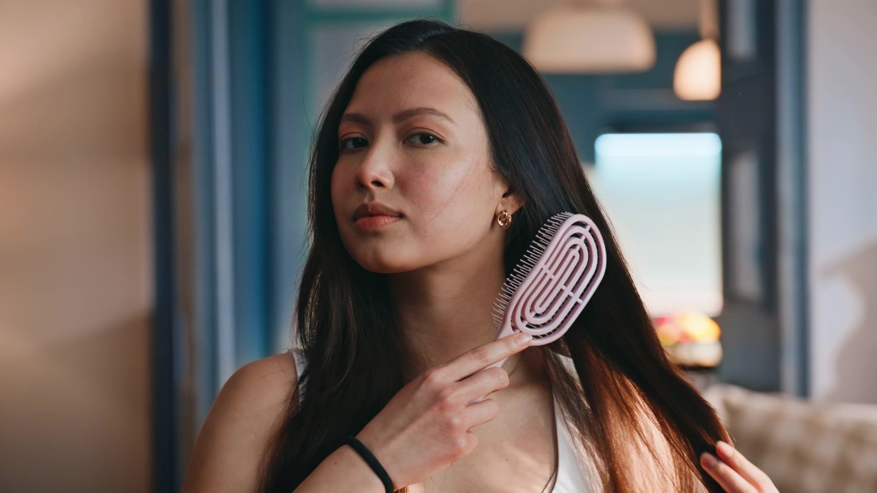 Young asian woman combing healthy shiny strands. Hair care beauty wellness routine