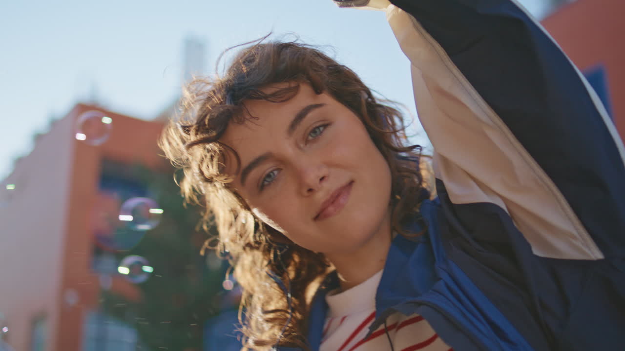 una mujer bonita bailando con las manos mirando a la cámara en la calle soleada de cerca.