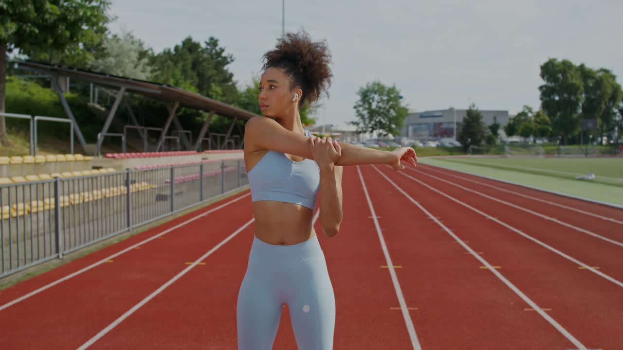 mujer estirándose en la pista de atletismo