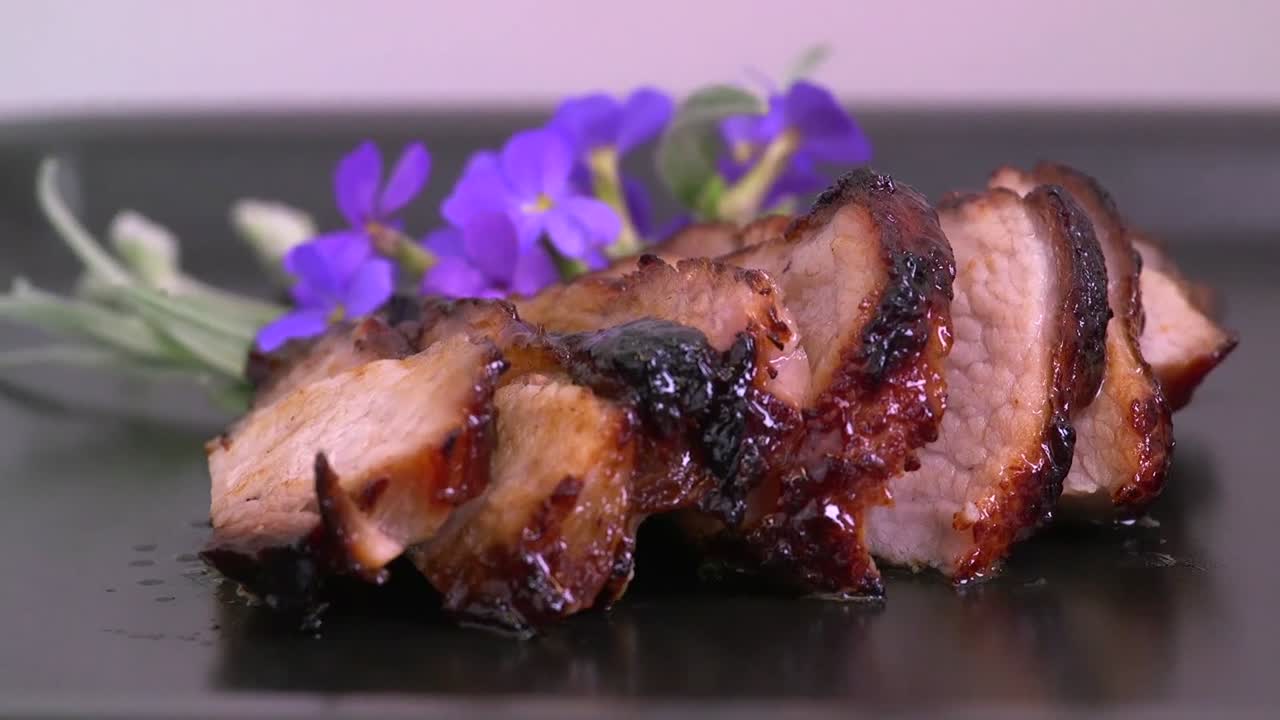 Mouthwatering footage of roast pork sizzling to perfection, featuring golden-brown crackling and tender, juicy meat.The video captures the rich textures and savory appeal of a well seasoned pork roast
