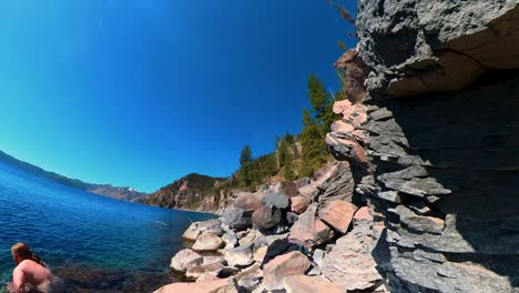 A-red-haired-man-goes-for-a-swim-in-Crater-Lake-National-Park-surrounded-by-blue-water-and-blue-sky