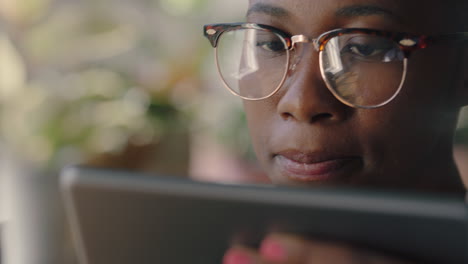 close up portrait beautiful african american woman using digital tablet computer in cafe drinking coffee browsing online reading social media messages watching entertainment wearing glasses