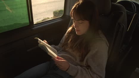 Mujer-Viajera-Leyendo-Un-Libro-En-Una-Camioneta-Al-Atardecer