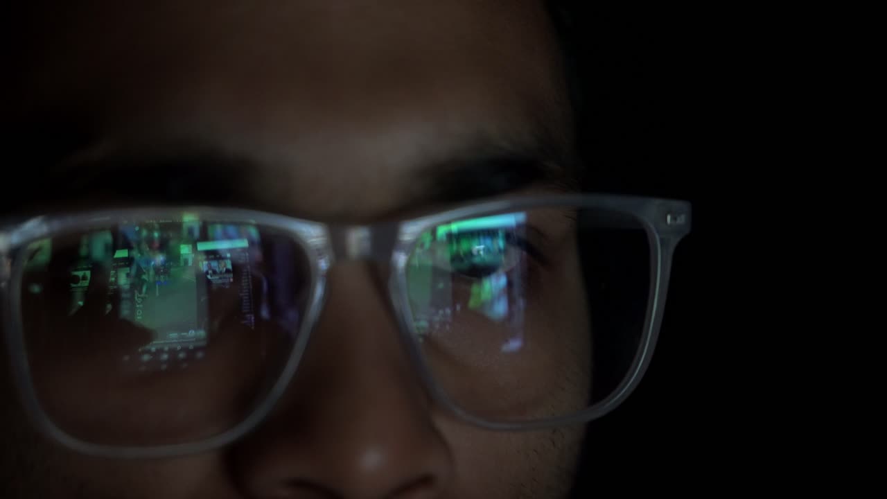 Adult Indian man smartphone user with eyeglasses doomscrolling through social media reels in dark room, Closeup of eyes