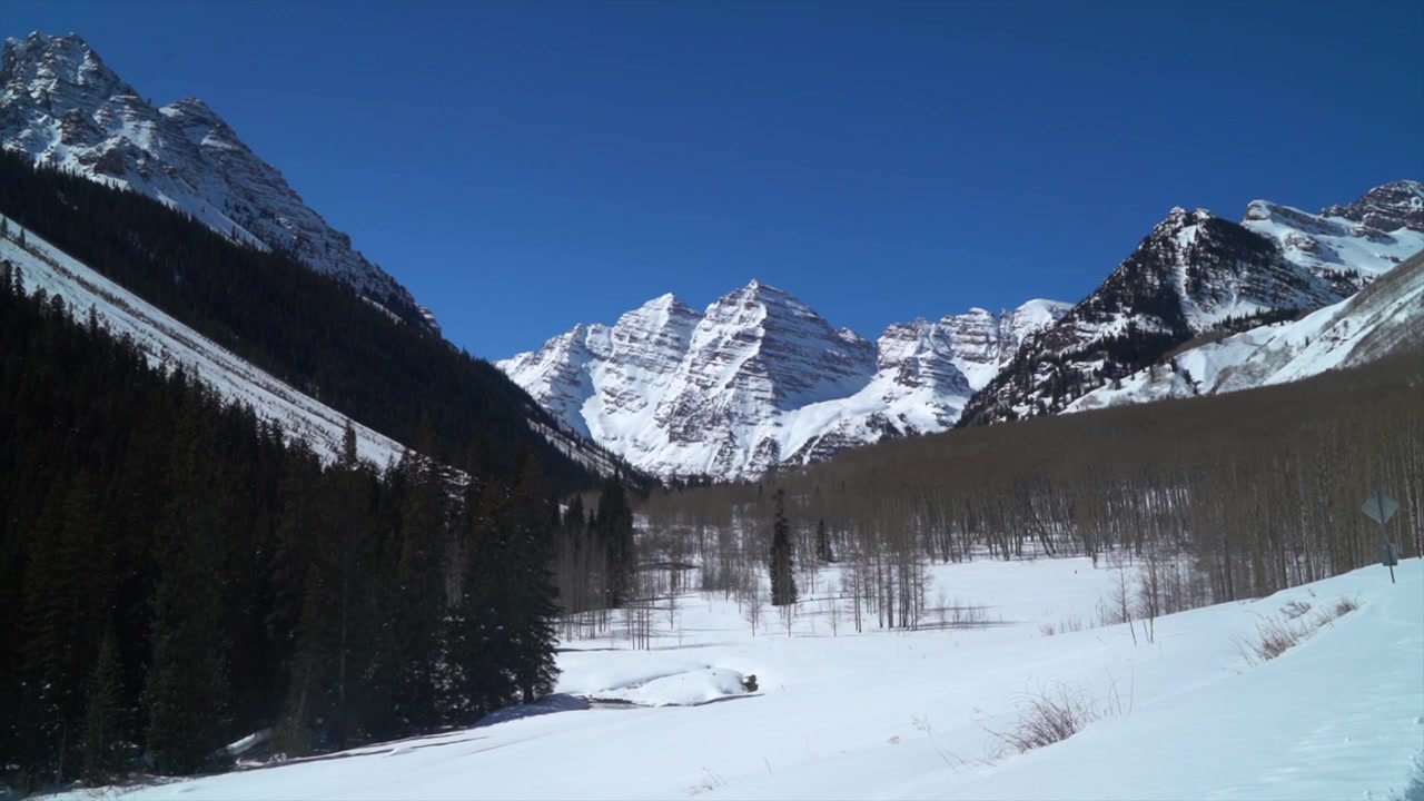 Neve farinosa profonda a Maroon Bells, Vetta Nord Maroon Peak, Aspen innevata, Colorado. Periodo invernale e primaverile nelle Montagne Rocciose. Lago Maroon, sentiero per motoslitte ed escursioni, mattinata soleggiata, cielo azzurro. Capitol Peak, panoramica del tour del ranch Lazy 7.